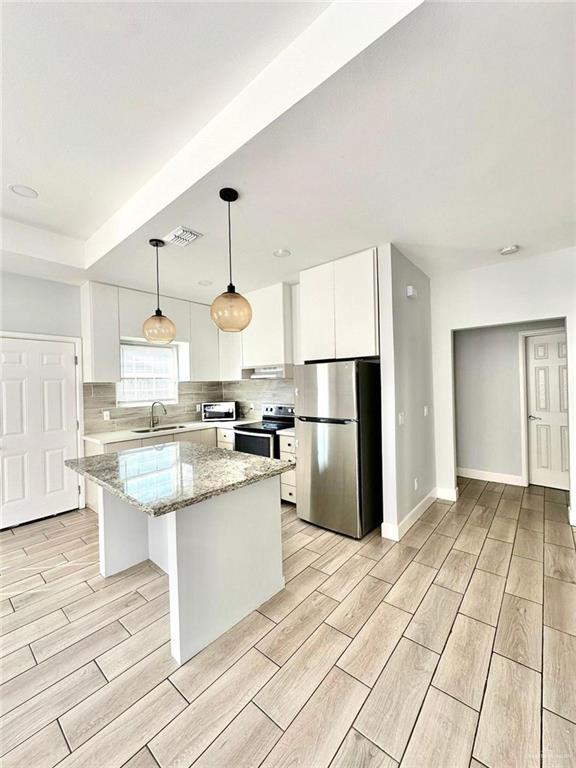 kitchen with white cabinets, sink, a kitchen island, and appliances with stainless steel finishes