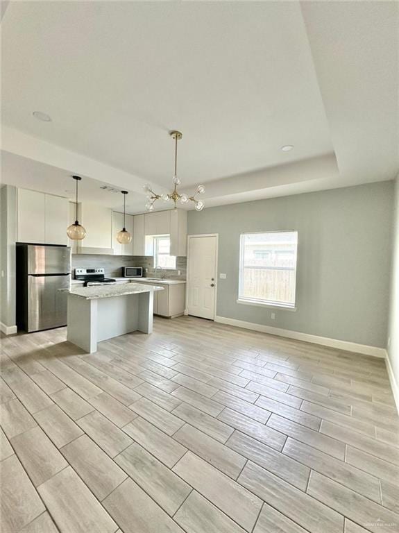 kitchen featuring hanging light fixtures, stainless steel appliances, a kitchen island, light hardwood / wood-style flooring, and white cabinets