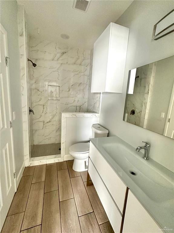 bathroom featuring tiled shower, vanity, and toilet