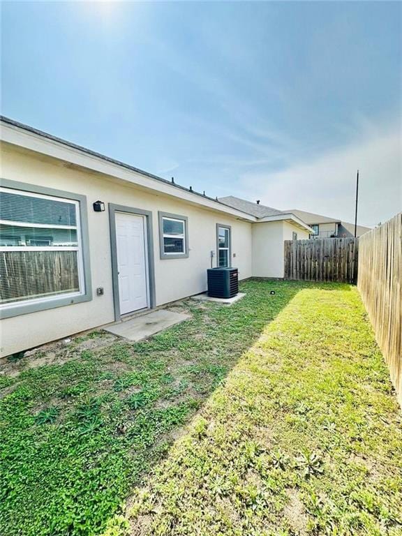 back of house featuring a lawn and central AC