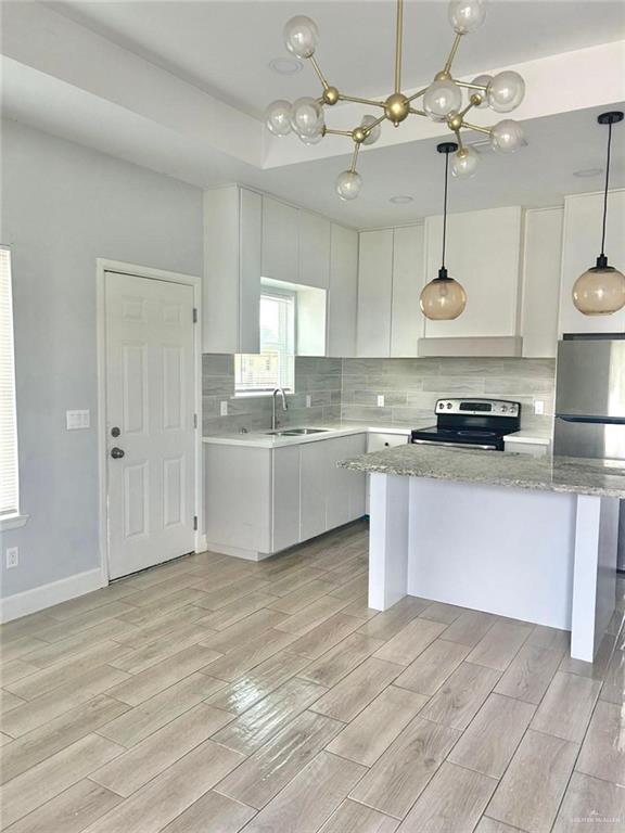 kitchen with sink, hanging light fixtures, light hardwood / wood-style flooring, white cabinetry, and stainless steel appliances