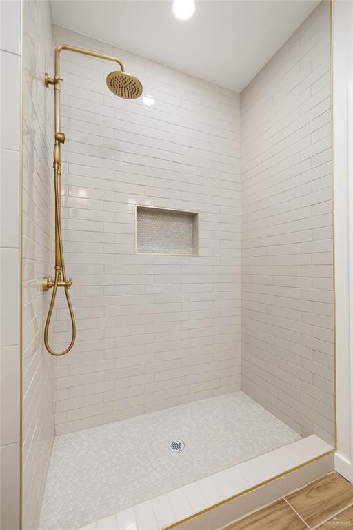 bathroom with a tile shower and wood-type flooring