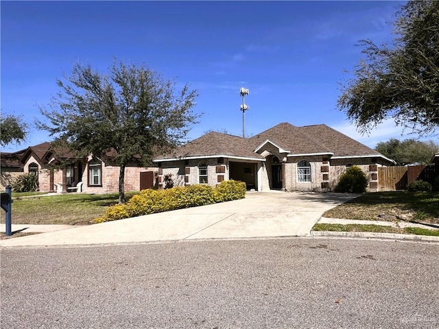 view of front of house featuring concrete driveway, brick siding, a shingled roof, and fence