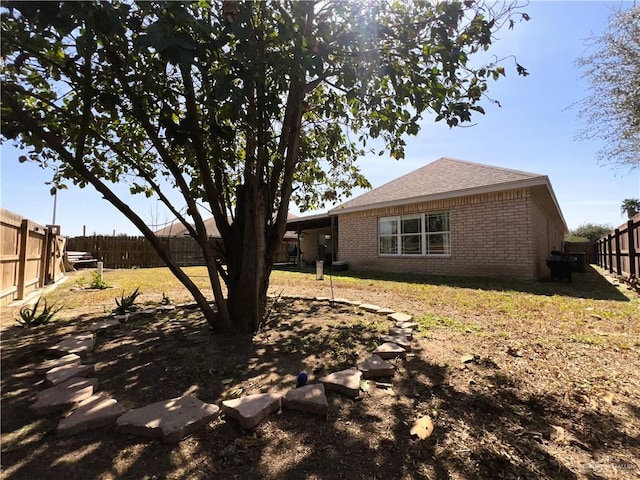 back of property featuring brick siding and a fenced backyard