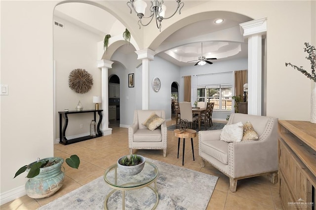 interior space with light tile patterned floors, arched walkways, ornate columns, and ceiling fan with notable chandelier