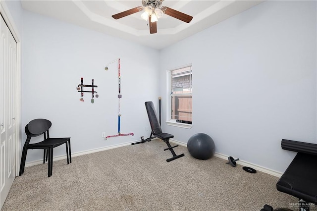 exercise room featuring ceiling fan, carpet floors, a raised ceiling, and baseboards