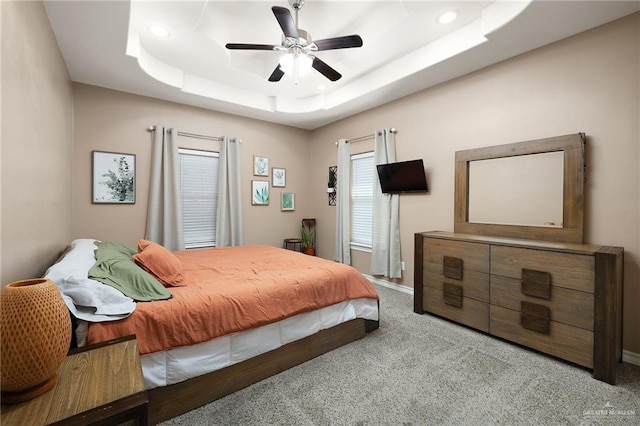 carpeted bedroom featuring a tray ceiling, ceiling fan, baseboards, and recessed lighting