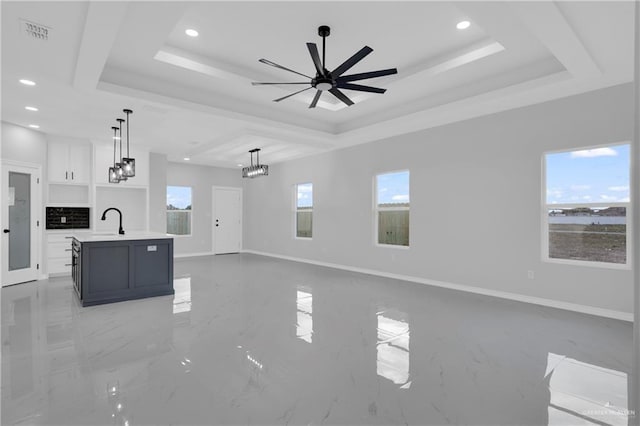 unfurnished living room featuring a tray ceiling, ceiling fan, and sink