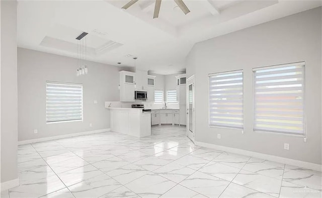 kitchen featuring a tray ceiling, hanging light fixtures, white cabinets, and appliances with stainless steel finishes