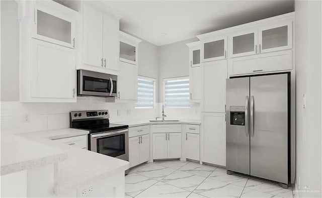 kitchen with sink, white cabinetry, decorative backsplash, and stainless steel appliances