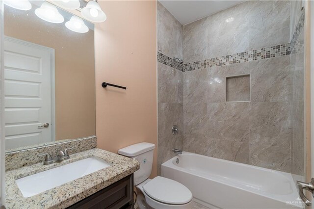 full bathroom featuring vanity, tiled shower / bath combo, and toilet