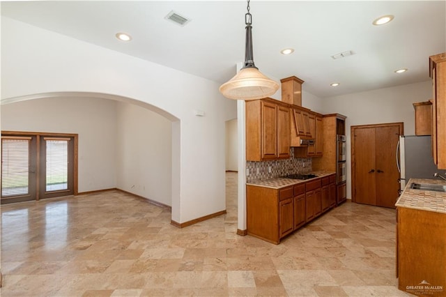 kitchen with backsplash, pendant lighting, stainless steel appliances, and sink