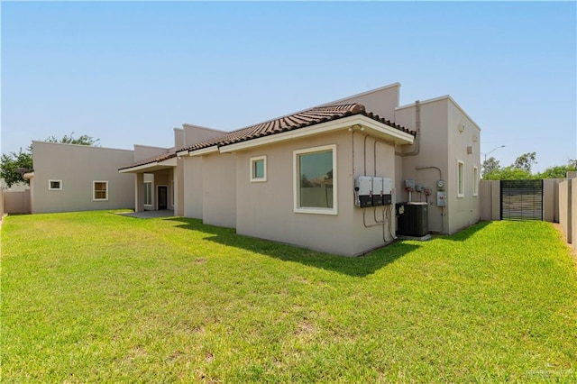 back of property featuring central AC unit and a lawn