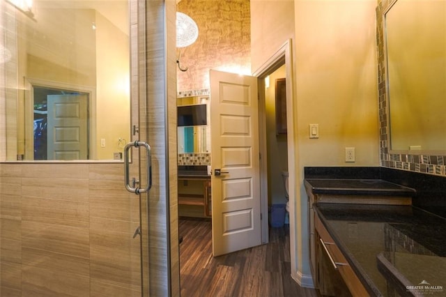 bathroom featuring hardwood / wood-style flooring, toilet, tasteful backsplash, and a shower with shower door