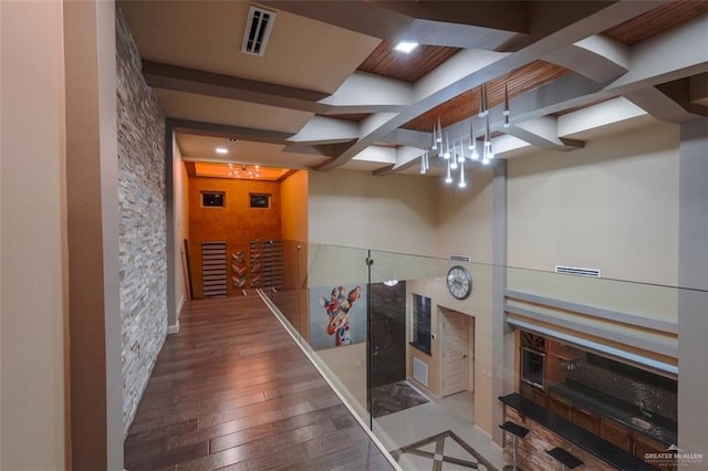 corridor with beam ceiling and hardwood / wood-style floors