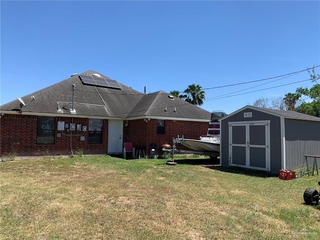 back of house featuring solar panels, a yard, and a storage shed