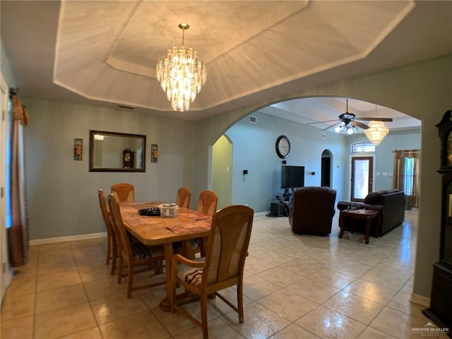 tiled dining space with a raised ceiling and ceiling fan with notable chandelier