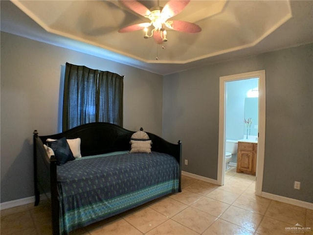 tiled bedroom with ceiling fan, connected bathroom, and a tray ceiling