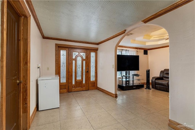 tiled foyer featuring a healthy amount of sunlight, a textured ceiling, and ornamental molding