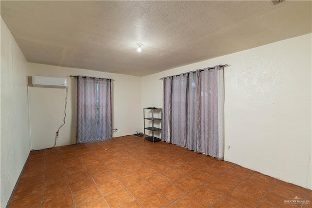 empty room with a wall mounted air conditioner and a textured ceiling