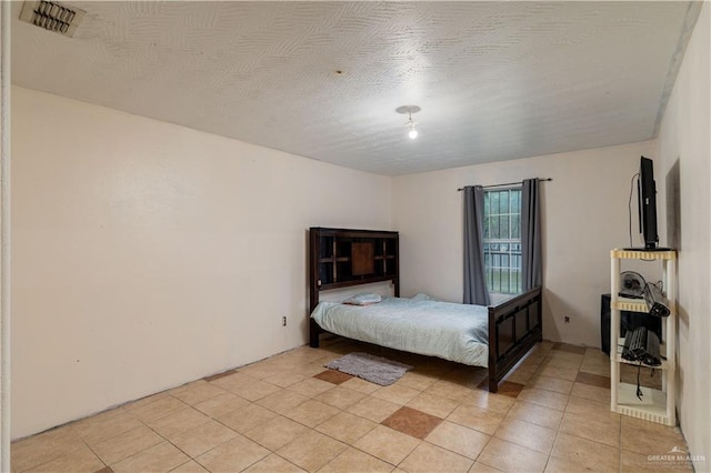 bedroom with a textured ceiling and light tile patterned flooring