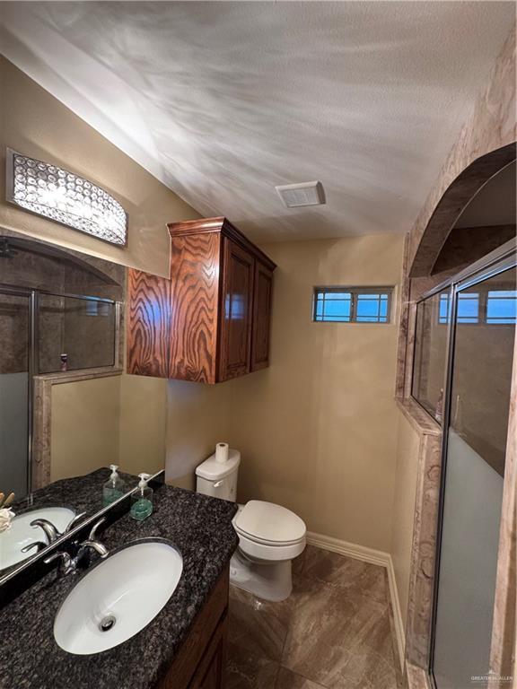 full bathroom featuring a stall shower, visible vents, baseboards, toilet, and vanity