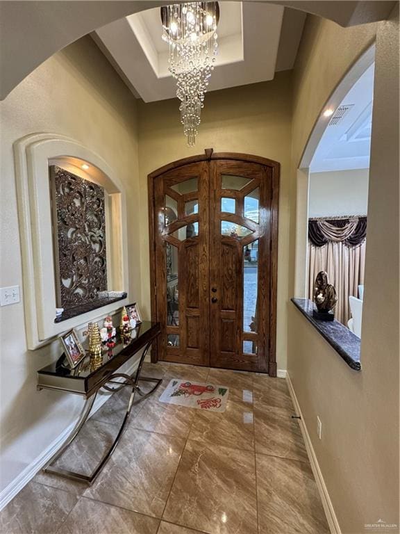 entrance foyer featuring a notable chandelier, arched walkways, a towering ceiling, and baseboards