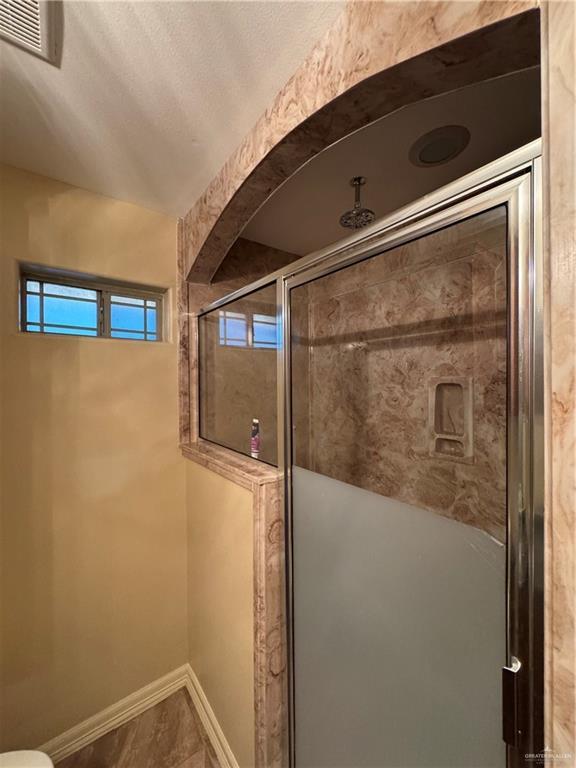 bathroom with a shower stall, visible vents, and baseboards