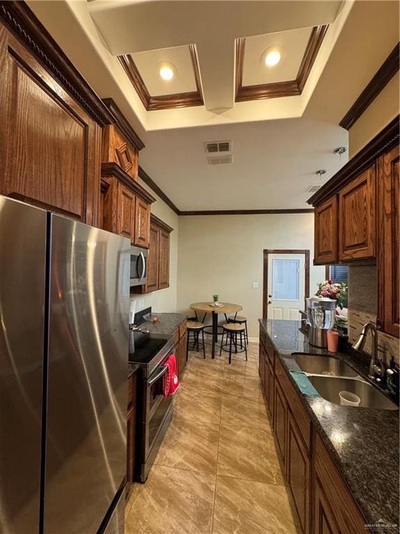 kitchen with a sink, visible vents, ornamental molding, appliances with stainless steel finishes, and dark stone counters