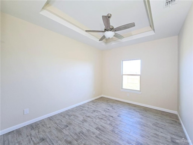 empty room featuring hardwood / wood-style floors, a tray ceiling, and ceiling fan