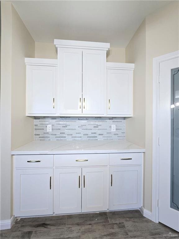 bar featuring white cabinets, decorative backsplash, and dark wood-type flooring