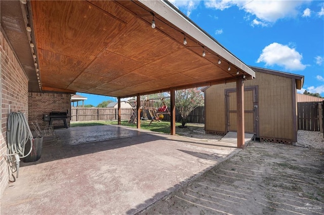 2103 W 30th St, Mission, TX 78574 - view of patio featuring a storage unit, a fenced backyard, an outbuilding, and a playground