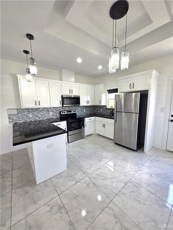 kitchen featuring white cabinets, pendant lighting, stainless steel appliances, and tasteful backsplash