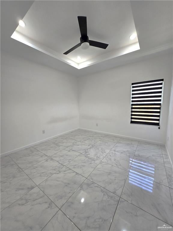 unfurnished room with ceiling fan and a raised ceiling