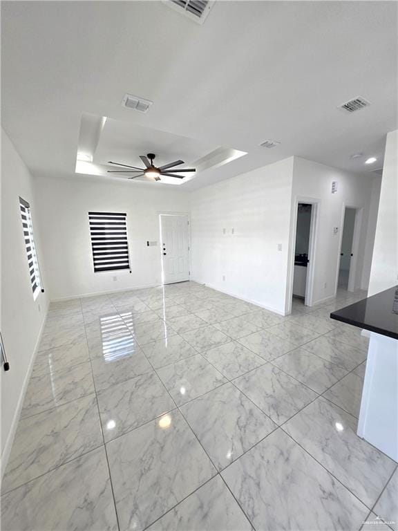 empty room featuring ceiling fan and a tray ceiling