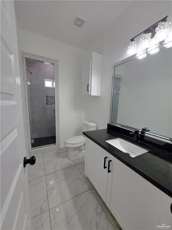 bathroom featuring vanity, toilet, and a shower with door