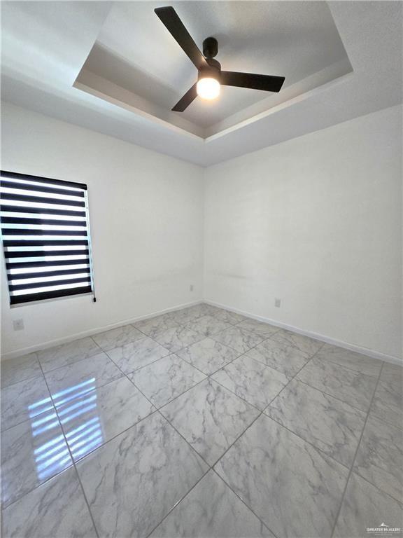 empty room with a raised ceiling and ceiling fan