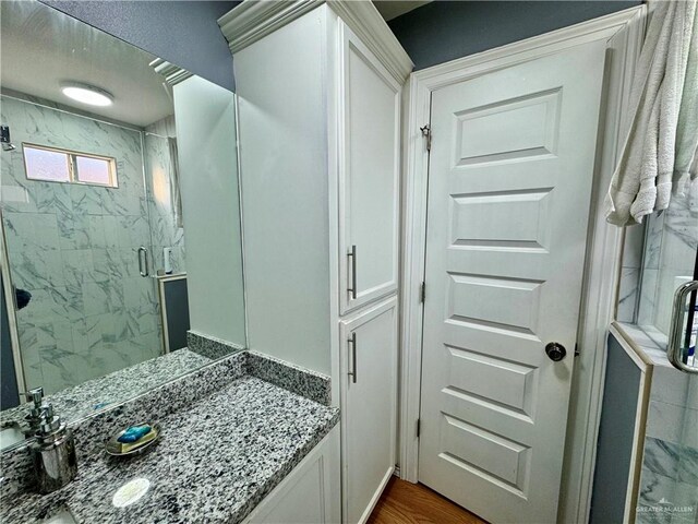 bathroom with hardwood / wood-style floors, vanity, and a shower with door