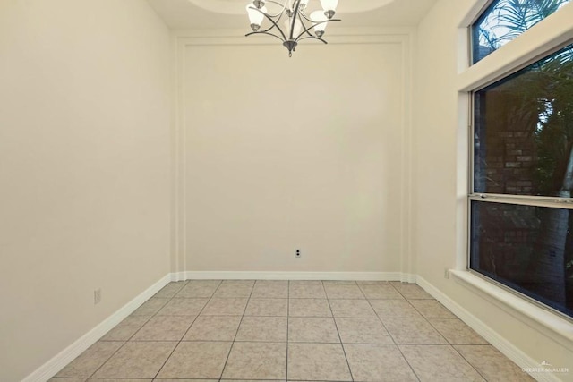 tiled empty room featuring a chandelier