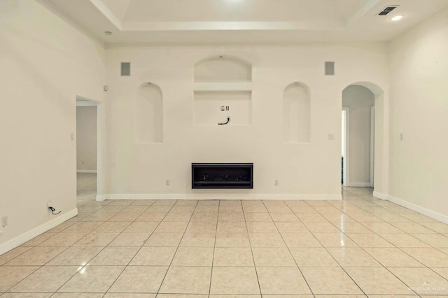 unfurnished living room featuring light tile patterned floors, a towering ceiling, and a raised ceiling