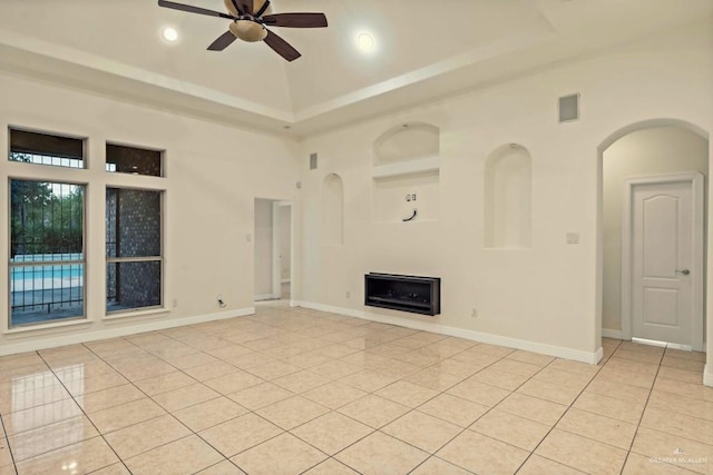 unfurnished living room featuring ceiling fan, light tile patterned floors, and a towering ceiling