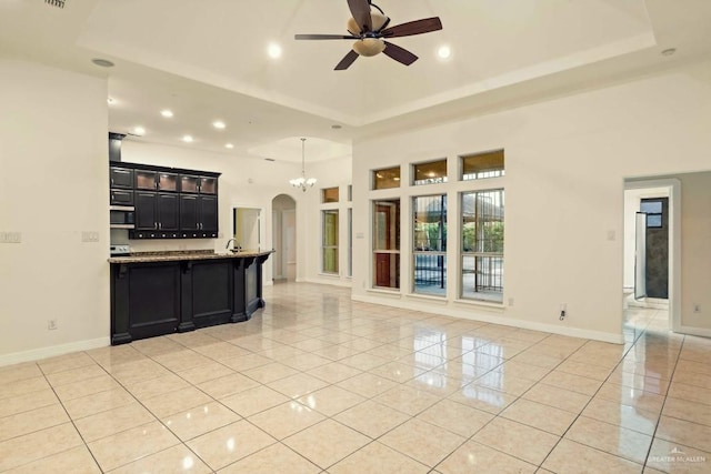 kitchen with light tile patterned floors, a raised ceiling, ceiling fan, and light stone counters