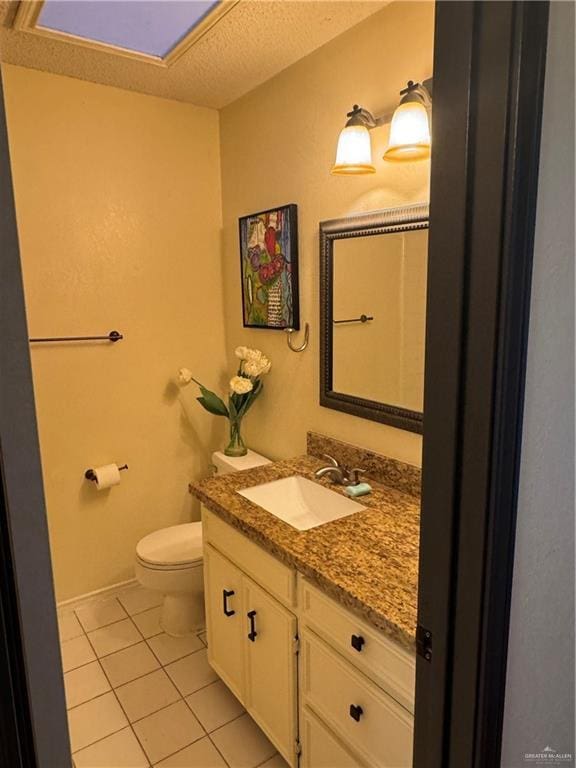 bathroom featuring vanity, toilet, tile patterned flooring, and a textured ceiling