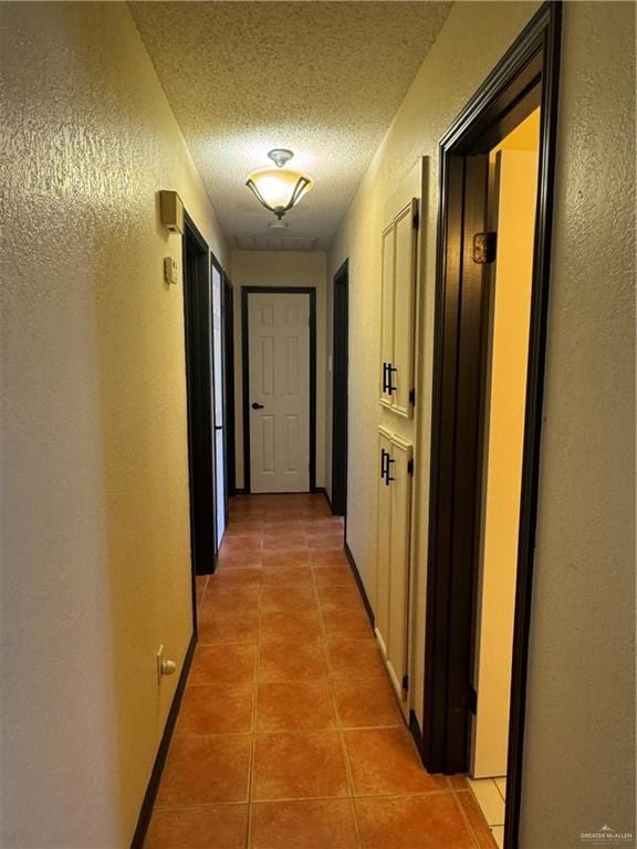 hall featuring tile patterned floors and a textured ceiling