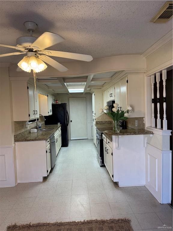 kitchen featuring white cabinetry, stainless steel appliances, kitchen peninsula, and dark stone counters