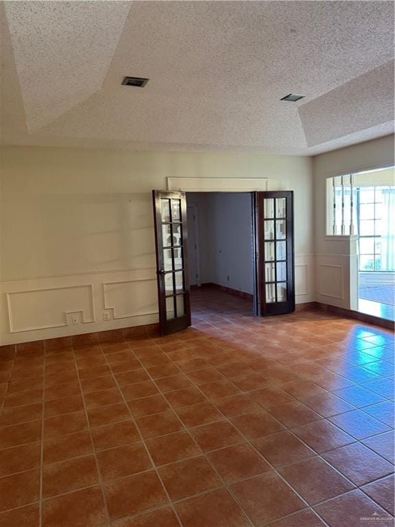 tiled spare room featuring french doors and a textured ceiling