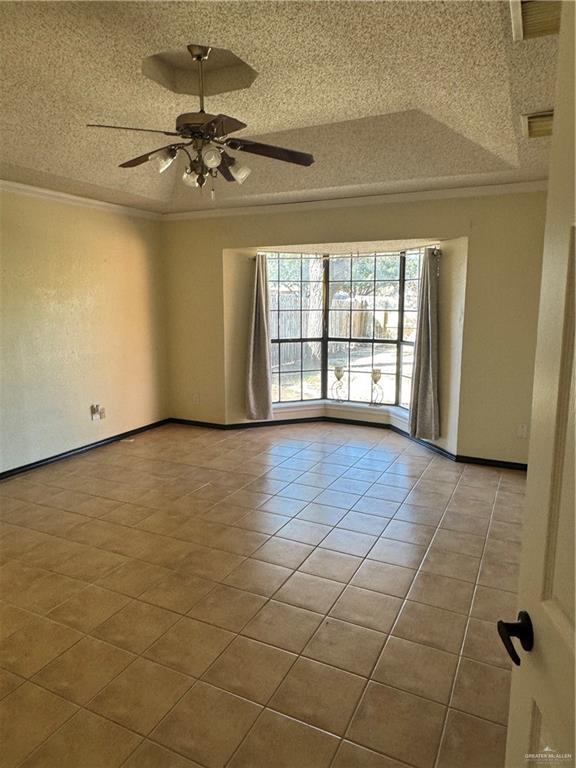 spare room with crown molding, light tile patterned floors, ceiling fan, and a textured ceiling