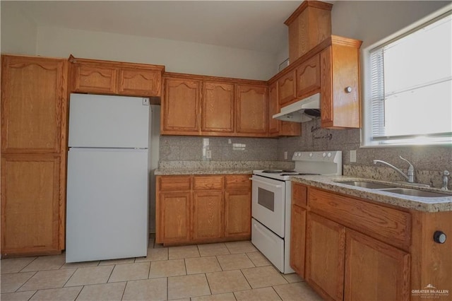 kitchen featuring light tile patterned floors, backsplash, white appliances, light stone countertops, and sink