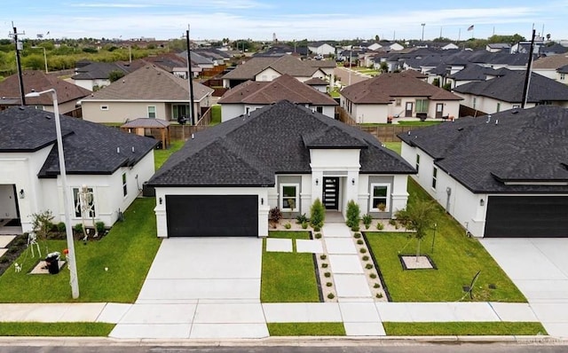 view of front of home featuring a garage, a shingled roof, concrete driveway, a residential view, and a front yard