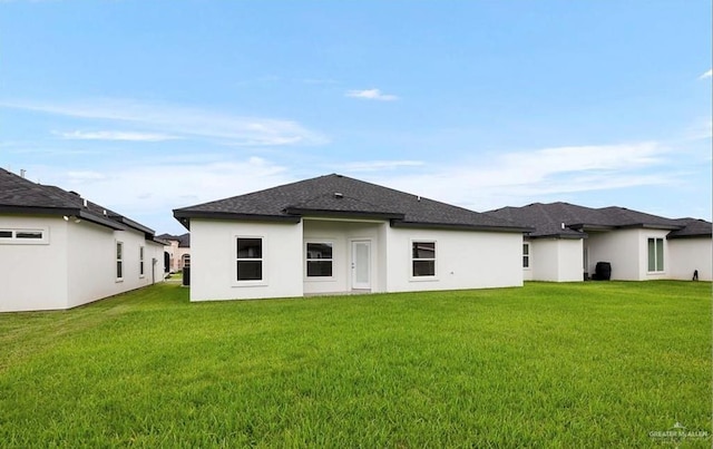 rear view of property with stucco siding and a yard